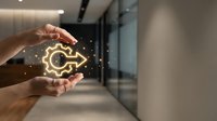 Hands holding glowing gear symbol with sparkling light effects in modern office corridor, representing innovation, technology solutions, and business optimization.