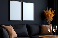 Modern dark interior with black sofa, empty white frames, wheat bouquet and wine glasses on wooden table against deep teal wall, luxury home decor.