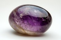 Polished oval amethyst crystal with natural inclusions and color gradients from deep purple to clear, showcasing raw mineral formation on white background.