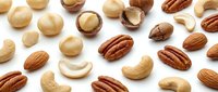 Mixed nuts collection with almonds cashews pecans and macadamias scattered on white background for healthy snacking and cooking ingredients.