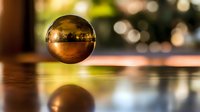 Golden crystal sphere floating above reflective wooden surface with warm bokeh lights creating magical ambiance for meditation and mindfulness practices.