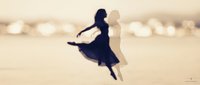 Woman in flowing dark dress leaping joyfully against blurred bokeh background, conveying freedom, happiness and movement for lifestyle and inspirational content.