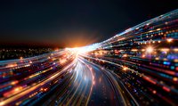 Abstract light trails and motion blur creating dynamic streaks of blue and orange illumination against dark background, technology concept for digital speed.