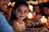 Young Asian girl in lace dress smiling warmly at festive dinner table with bokeh lights and candles creating magical holiday atmosphere during family celebration.