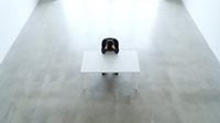 Lone businessman sitting at white desk in empty modern office space with polished concrete floors, minimalist workspace for corporate concepts.