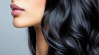 Close up profile view of glossy pink lips and flowing dark wavy hair against light background, showcasing natural beauty and hair care styling.