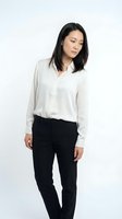 Young East Asian woman wearing cream button-up shirt and black trousers, standing against white background for corporate, business, and professional styling applications.