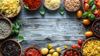 Italian cuisine ingredients frame on rustic wooden background with pasta, spices, herbs, tomatoes and olives. Fresh cooking concept with copy space for menu or recipe.