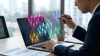 Professional businessman analyzing colorful holographic data visualization on laptop screen in modern office environment for business intelligence and analytics.