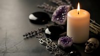 Mystical altar setup with burning candle, amethyst crystals, lavender, pentagram symbols and skull for spiritual rituals and occult practices.