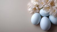 Soft pastel blue Easter eggs with delicate white spring flowers on neutral beige background, creating gentle holiday composition with copy space.