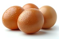 Fresh brown chicken eggs with water droplets on smooth shells arranged on white surface, soft natural lighting creates subtle shadows and highlights texture.