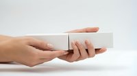 Hands holding white blank box package on clean background for product presentation and mockup design projects.