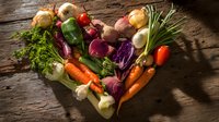 Fresh vegetables arranged in heart shape on rustic wooden background, symbolizing healthy eating and love for nutritious food.