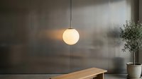 Minimalist interior with glowing spherical pendant lamp suspended above wooden table, potted plant, and frosted glass wall backdrop for modern home decor.