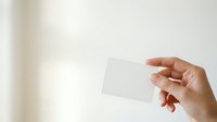 Hand holding blank white card against neutral background, suitable for business branding, marketing mockups, and corporate identity presentations.
