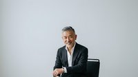 Mature male professional with gray hair and Middle Eastern ethnicity wearing dark blazer and white shirt, seated against white background for corporate portraits and business headshots.