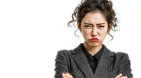 Young Asian businesswoman with crossed arms showing angry frustrated expression in gray suit jacket isolated on white background for corporate concepts.
