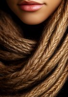 Close-up of African American woman's plump lips and blonde box braids against dark background, showing modern beauty and hairstyling trends for cosmetics marketing.