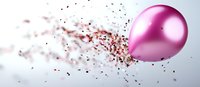Pink metallic balloon bursting and scattering small particles in motion against light background, captured in high-speed photography for dynamic effect.
