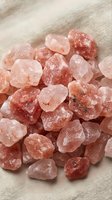Raw rose quartz crystals in various sizes displayed on neutral fabric background. Suitable for wellness, spirituality, and mineral collection content.