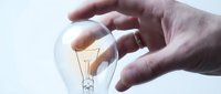 Hand protecting glowing light bulb symbolizing innovation, creativity and bright ideas for business solutions and inspiration concepts.