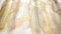 Abstract watercolor background with soft golden yellow and peachy pink brushstrokes creating gentle flowing texture for artistic design projects.