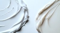 Creamy white cosmetic texture smears showing smooth skincare product consistency against light background, demonstrating luxurious moisturizer or face cream texture.