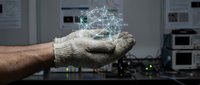 Male technician in work gloves holding digital network hologram above palm in modern server room laboratory environment for technology and innovation concepts.
