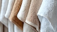 Fresh clean folded bath towels in neutral beige and white colors arranged in rows, showing soft terry cloth texture and layers for spa, hotel or home decor.