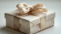Elegant white gift box decorated with champagne silk ribbon bow and delicate gold speckled pattern on textured paper, perfect for special occasions and celebrations.