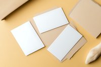 Blank white business cards and kraft paper envelopes arranged on neutral beige background for branding mockup and stationery design projects.