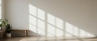 Minimalist interior room with natural sunlight casting geometric window shadows on white wall and wooden floor for modern home design concepts.