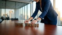 Businesswoman arranging wooden blocks spelling 2026 trends on a conference table in a modern office with city view.