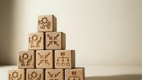 Wooden blocks stacked in pyramid formation with engraved business icons including people, connections, and organizational charts, representing corporate hierarchy and teamwork strategy.