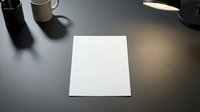 Blank white paper sheet on dark desk with coffee mug and lamp creating professional workspace atmosphere for business presentations and creative projects.