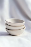 Stack of minimal white ceramic bowls on light background with soft shadows, modern minimalist tableware for food styling and restaurant presentation.
