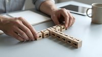 Businessman arranging wooden cubes with arrows into a cross shape on a desk, symbolizing strategy, direction, and decision-making.