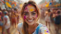 Young woman with bright colorful holi powder on face smiling joyfully at festival celebration, blonde hair and natural makeup under vibrant paint splashes.