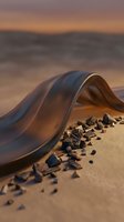 Flowing transparent fabric draped on sandy beach at golden hour sunset with scattered dark pebbles and warm ocean backdrop for luxury fashion concepts.