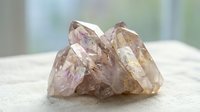 Natural smoky quartz crystal cluster with purple and golden hues on white surface, mineral specimen for healing, meditation, and home decor collection.