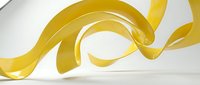 Golden yellow flowing ribbon waves creating elegant curved motion against clean white background for modern design projects.