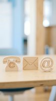 Wooden contact icons phone mail email symbols on desk representing communication methods for business customer service and support.