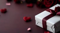 White gift box with burgundy ribbon and red roses on dark background with scattered heart decorations creates romantic Valentine's Day or anniversary mood.