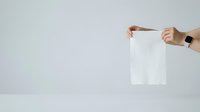 Person with medium skin tone holding blank white paper sheet against neutral background, suitable for advertising, marketing mockups, and promotional campaigns.