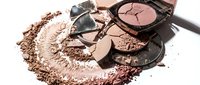 Broken makeup powder compacts with scattered cosmetic debris creating artistic beauty product composition for fashion and cosmetics industry applications.