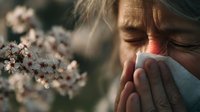 Senior woman with allergies sneezing into tissue near blooming spring flowers, illustrating seasonal pollen sensitivity and allergic reaction.