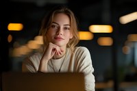 Young woman with thoughtful expression in cozy sweater at cafe, warm bokeh lights creating intimate atmosphere for lifestyle and portrait photography.
