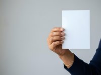 Male hand holding blank white paper card against neutral background, suitable for advertising, marketing campaigns, presentations, and promotional materials.