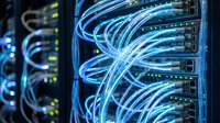 Fiber optic cables with blue illuminated light connected to server equipment in data center infrastructure for networking and telecommunications technology.